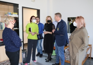 Viesi un SIVA darbinieces stāv psihologa nodarbību telpā un sarunājas.