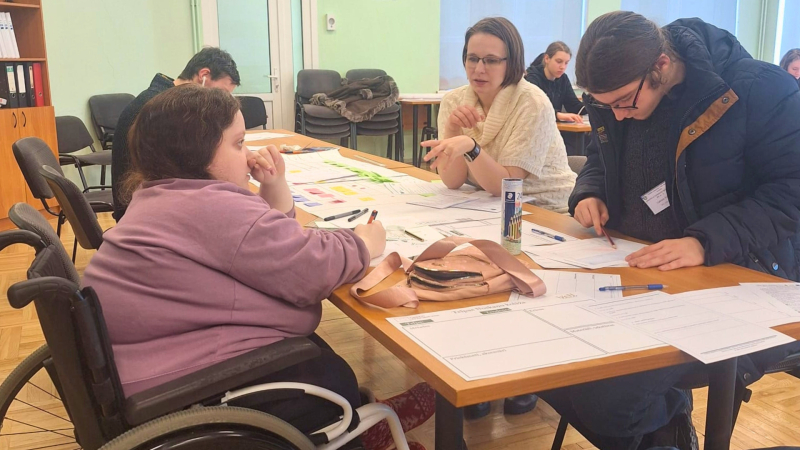 5.	Cilvēki sēž pie galda, runā u raksta uz papīra. Viņi kopā strādā pie uzdevuma.