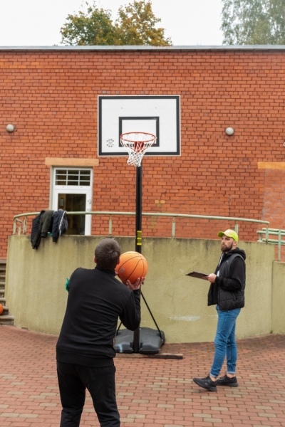 spēļu dalībnieks met basketbola bumbu grozā