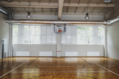 SIVA Koledžas sporta zāle, kurā redzams basketbola grozs, iezīmētas laukuma līnijas un zālē esošie logi
