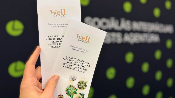 1.	Roka tur divus bukletus ar uzrakstu “Well home”. Uz bukletiem ir teksts par emocionālo dizainu un mazi augi attēla apakšā.