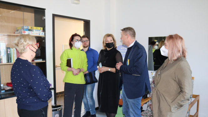 Viesi un SIVA darbinieces stāv psihologa nodarbību telpā un sarunājas.