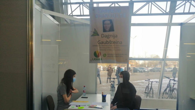 Pie balta galda sēž SIVA karjeras konsultante un skolēns. SIVA darbiniece sarunājas ar skolnieku.