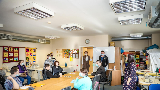 Mācību telpa, kurā pie galda sēž audzēkņi ar sejas un mutes aizsargmaskām un apgūst mācības klātienē