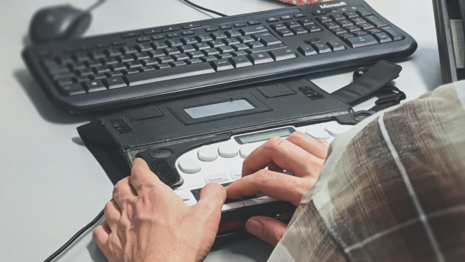 Cilvēks pie galda izmanto pielāgoto datora tastatūru