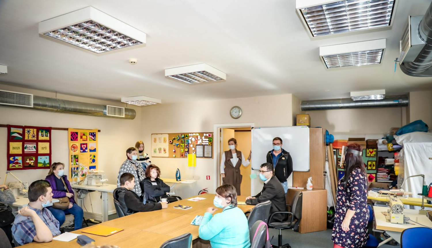 Mācību telpa, kurā pie galda sēž audzēkņi ar sejas un mutes aizsargmaskām un apgūst mācības klātienē
